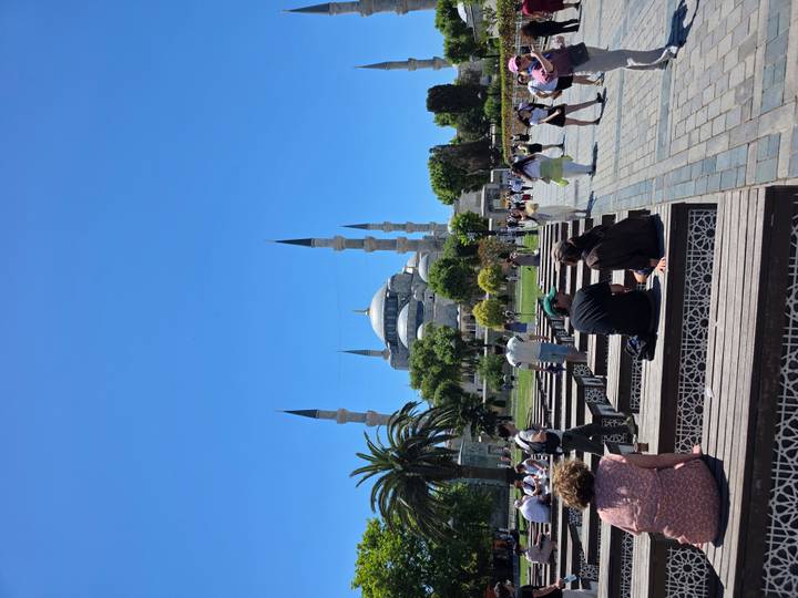 Visitors relaxing on benches facing the Blue Mosque across landscaped square.
