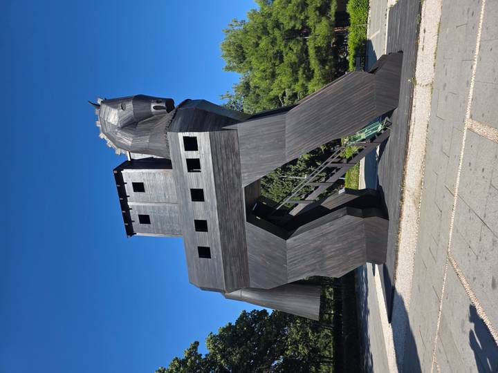 Large wooden replica of the Trojan Horse displayed outdoors against blue sky.