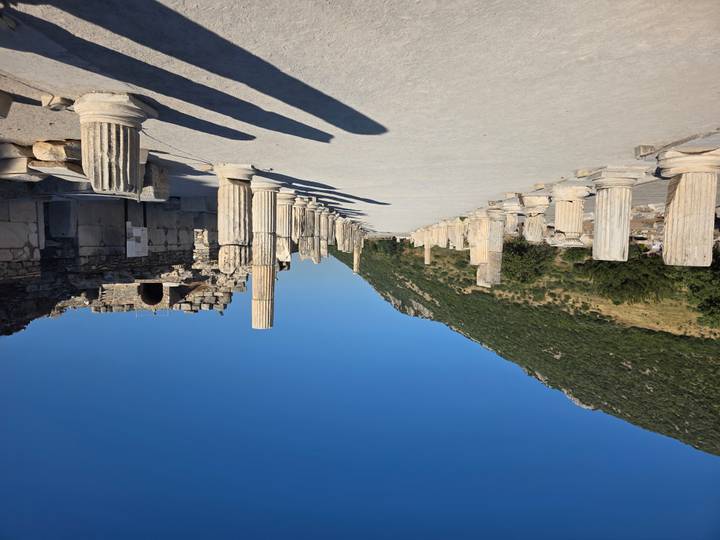 Ancient marble colonnaded street in Ephesus with hill backdrop and deep blue sky.