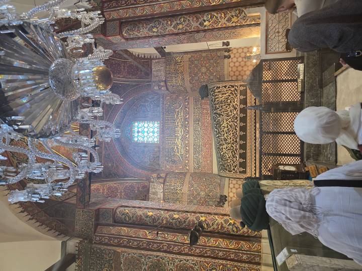 Pilgrims viewing ornate interior and sarcophagus inside Mevlana Museum in Konya.