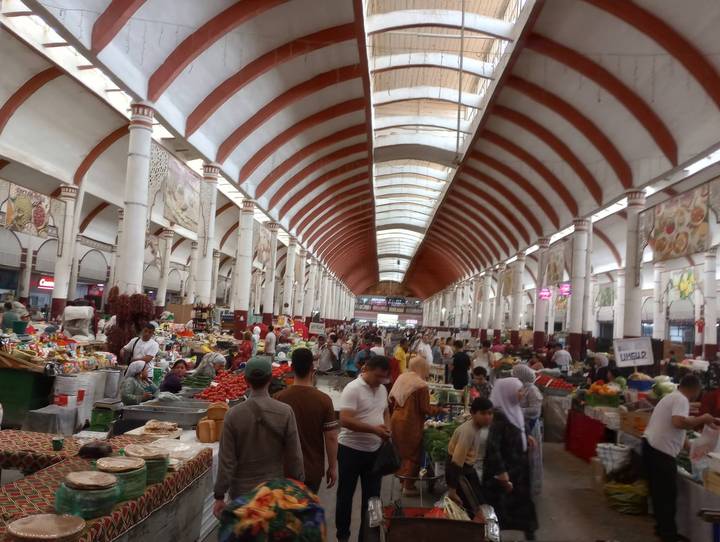 Lively produce market hall with arched ceiling packed with shoppers and stalls in Tashkent