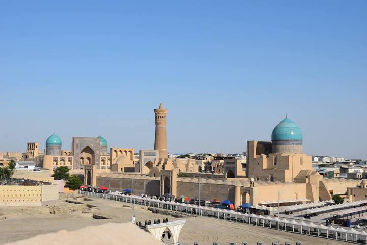 Panoramic skyline of Bukhara featuring Kalyan Minaret and turquoise domes against clear sky