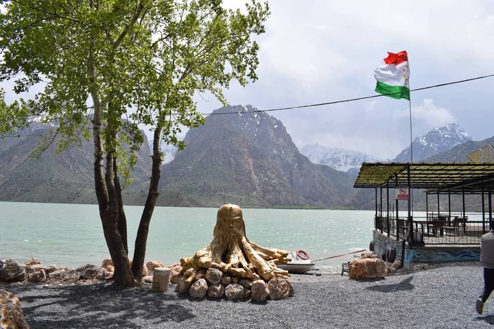 Mountain lake with Tajik flag and rustic lakeside café, Fann Mountains backdrop
