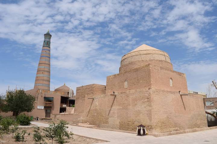 Brick mausoleum and minaret of Itchan Kala in Khiva under partly cloudy sky