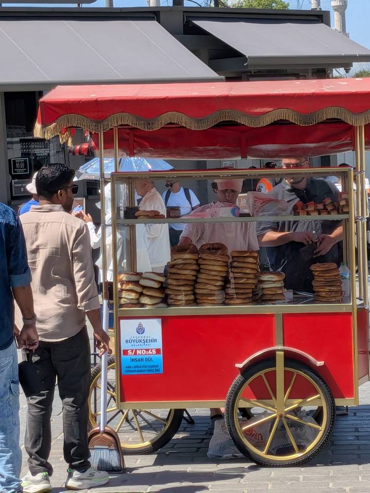 Street vendor stall in Istanbul selling stacks of simit bread with customers gathered around