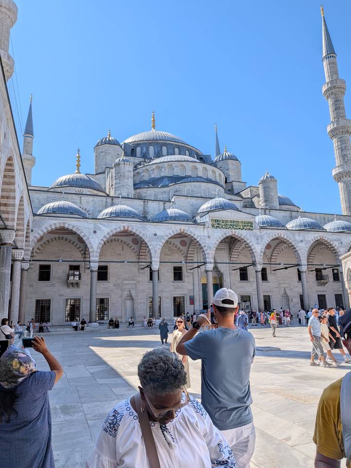 Courtyard of the Blue Mosque in Istanbul filled with tourists under a bright blue sky