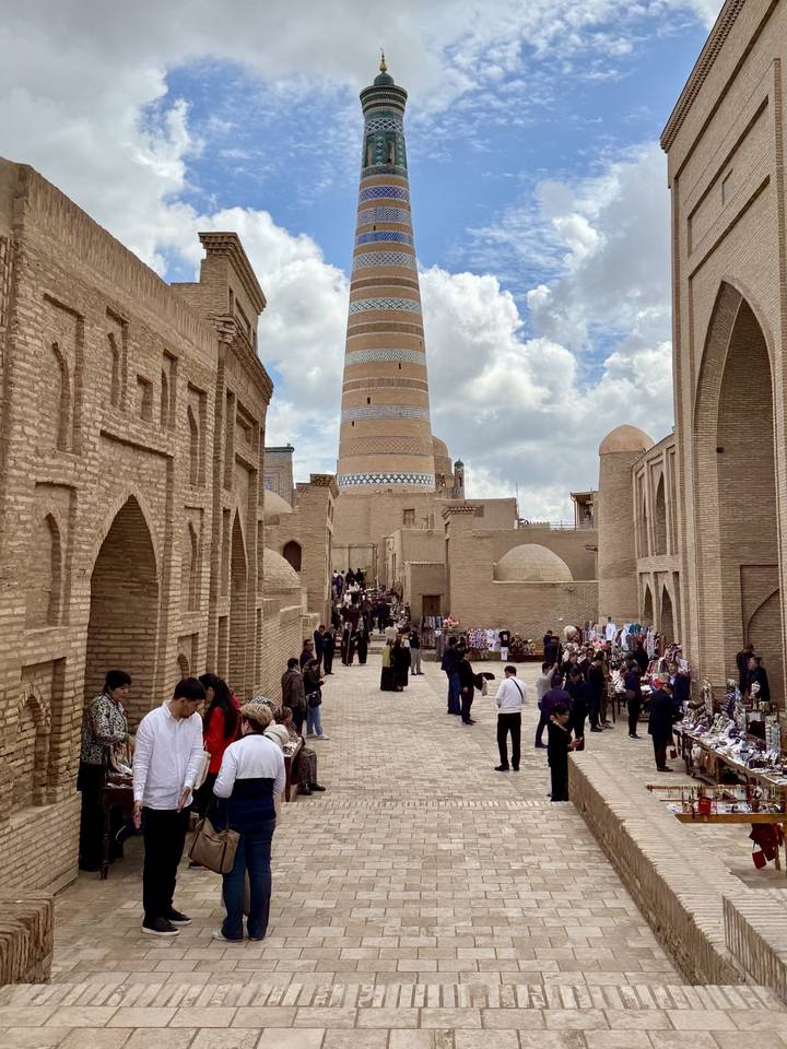Crowded ancient street in Khiva with iconic brick minaret towering in background