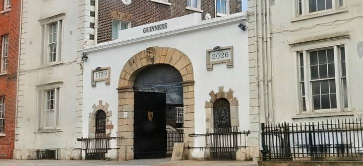 Historic Guinness gate with dates and crest set in a stone archway in Dublin.