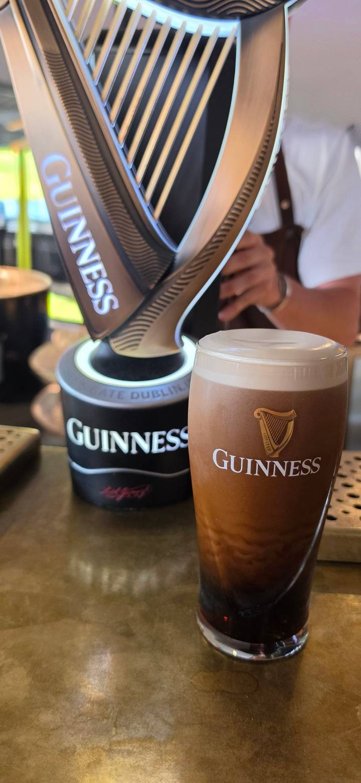 Freshly poured pint of Guinness in front of branded tap at a pub bar.