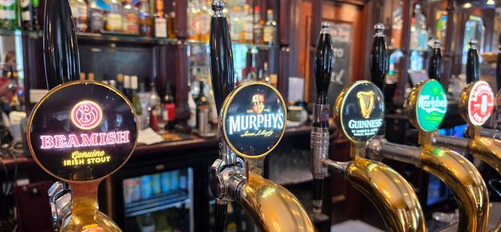 Row of polished beer taps showcasing Irish stouts and lagers in a traditional pub setting