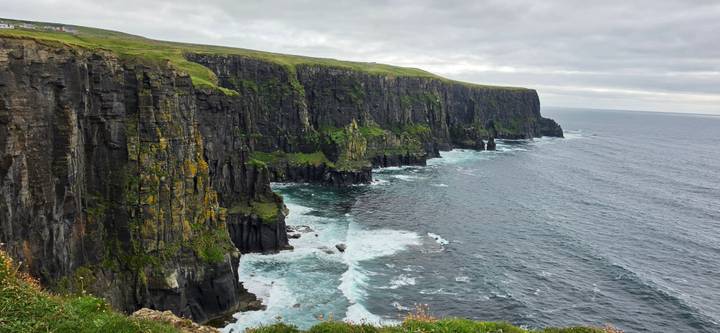 Dramatic Cliffs of Moher plunge into the Atlantic Ocean with waves crashing below