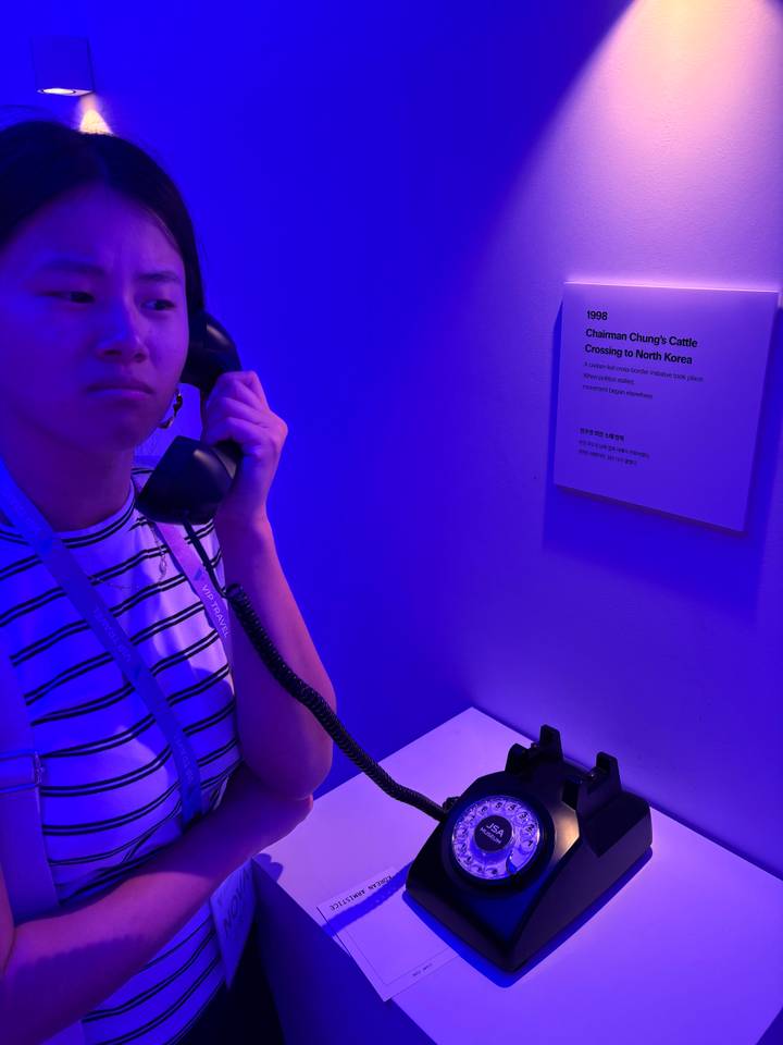 Woman on a museum tour holds a handset in the same blue-lit room