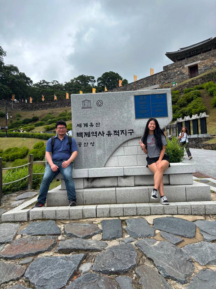 Repeat shot of travellers seated by the UNESCO Baekje Historic Areas stone sign