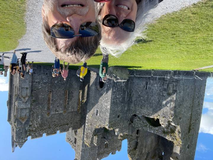 Visitors exploring the historic Rock of Cashel ruins on a sunny day, with stone walls and grassy grounds.