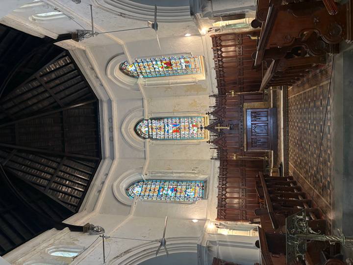 Small chapel interior with dark wooden pews, stained glass windows and a simple altar.