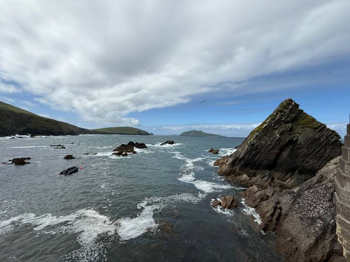 Dramatic rugged Atlantic coastline with jagged rocks and rolling waves under partly cloudy sky