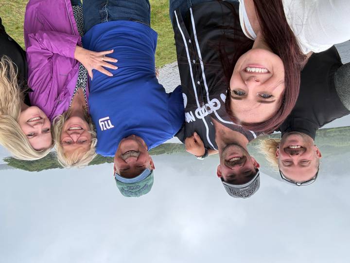 Group selfie by a misty lake and green hills on an overcast day