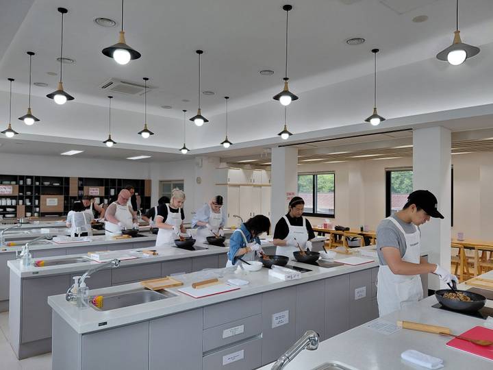 Cooking class with participants preparing dishes at individual workstations in a bright modern kitchen