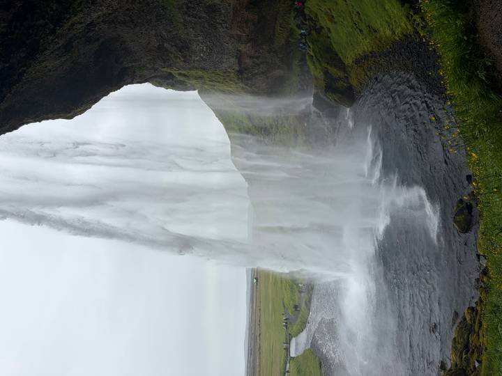 Dramatic side-view from behind Seljalandsfoss waterfall with water plunging into a circular pool