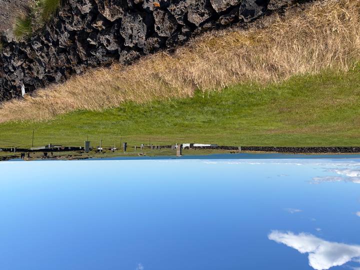 Sparse cliff-edge cemetery with scattered headstones overlooking the ocean on a clear day