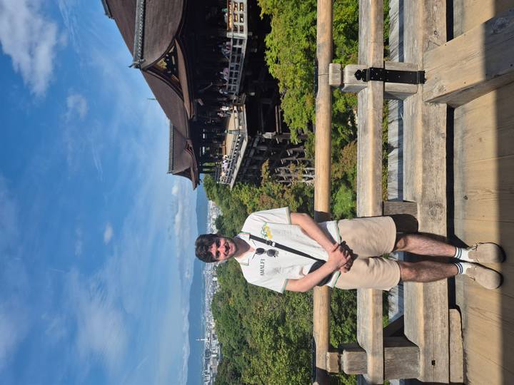 Visitor stands on the wooden terrace of Kiyomizu-dera overlooking Kyoto city.