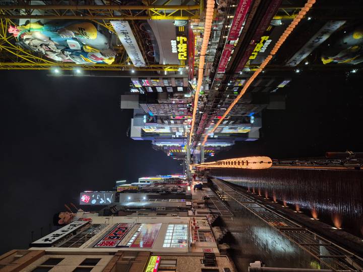 Night view of the illuminated Dotonbori canal with colorful reflections in the water.