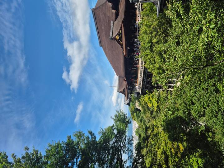 Wide view of Kiyomizu-dera temple perched on a green hillside under a clear sky.
