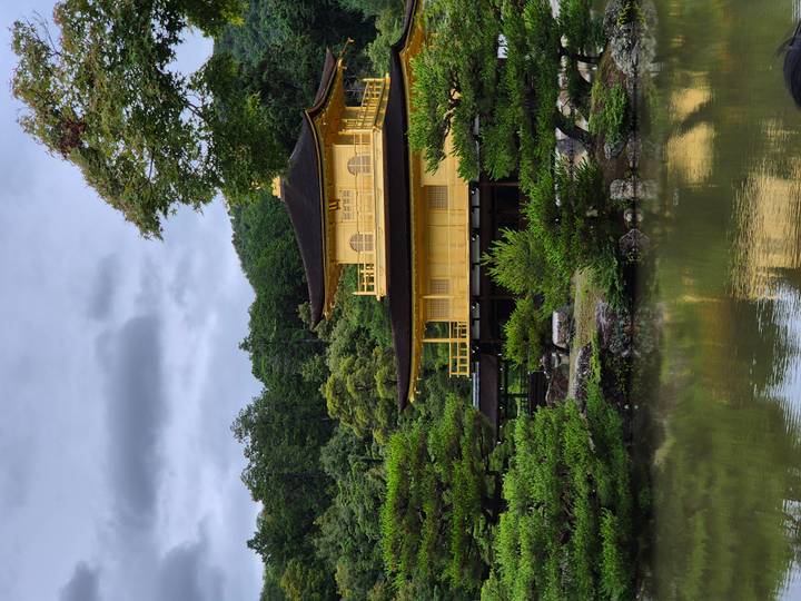 Golden Pavilion temple reflected in a calm pond surrounded by lush greenery.