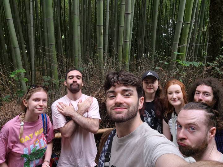 Group selfie among tall bamboo stalks in a tranquil forest path.