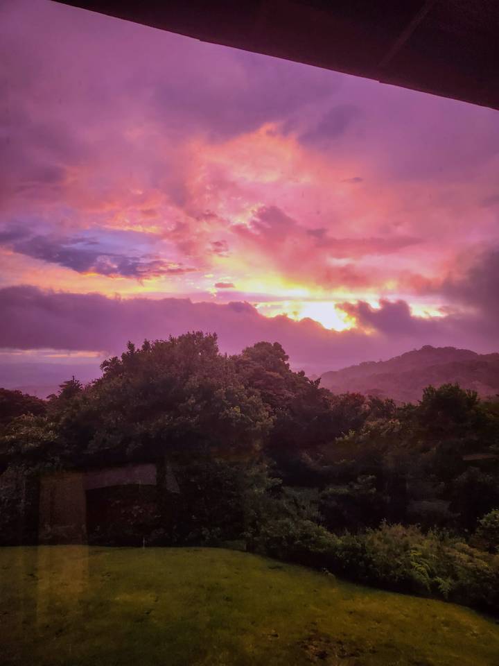 Vibrant pink and purple sunrise over mist-covered forested hills in Monteverde.