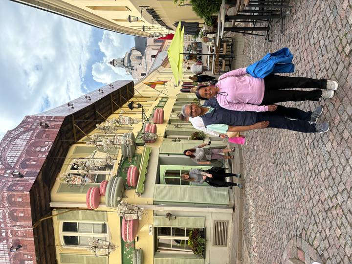 Couple stands on a cobblestone street lined with colourful historic buildings and outdoor cafés.