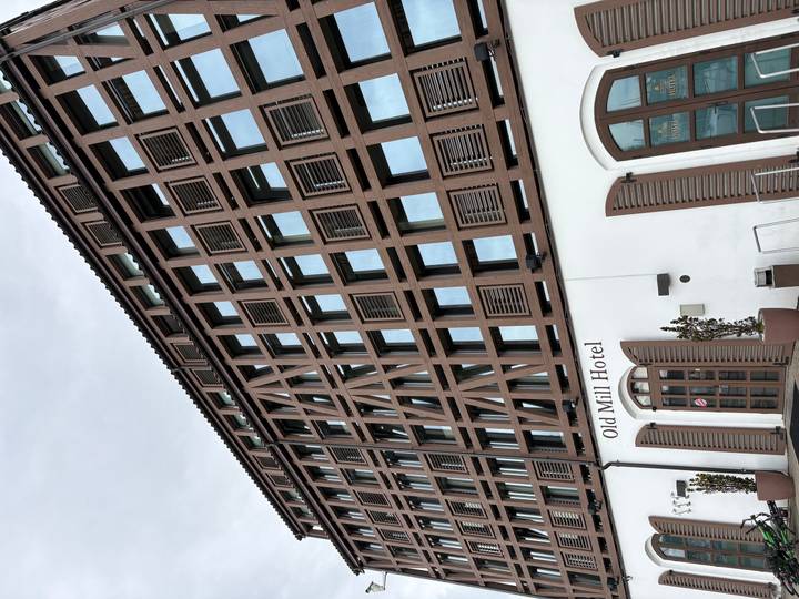 Facade of the timber-framed Old Mill Hotel with rows of large modern windows.