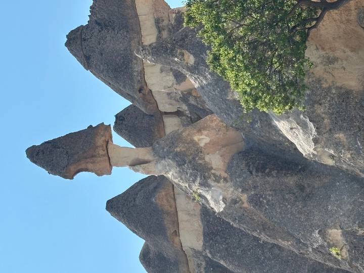 A tall fairy-chimney rock formation with a mushroom cap stands against a bright blue sky in Pasabag.