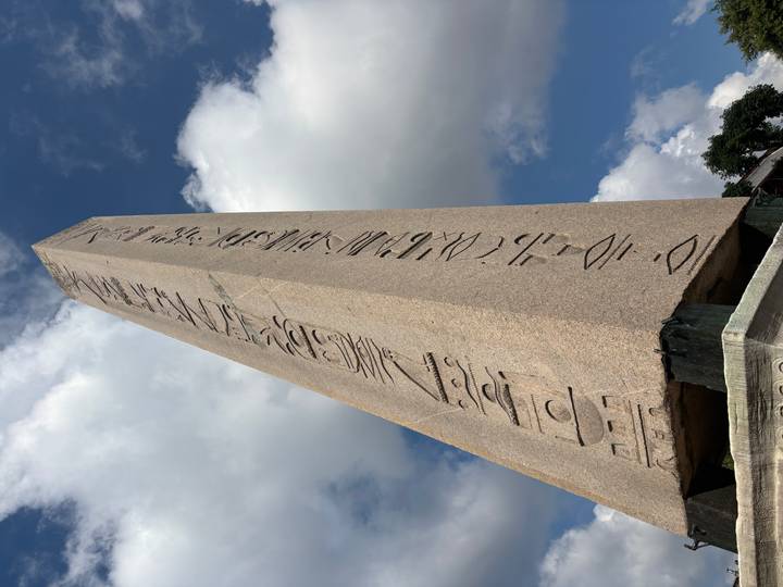 Low-angle close-up of the hieroglyph-covered Obelisk of Theodosius against a partly cloudy sky.