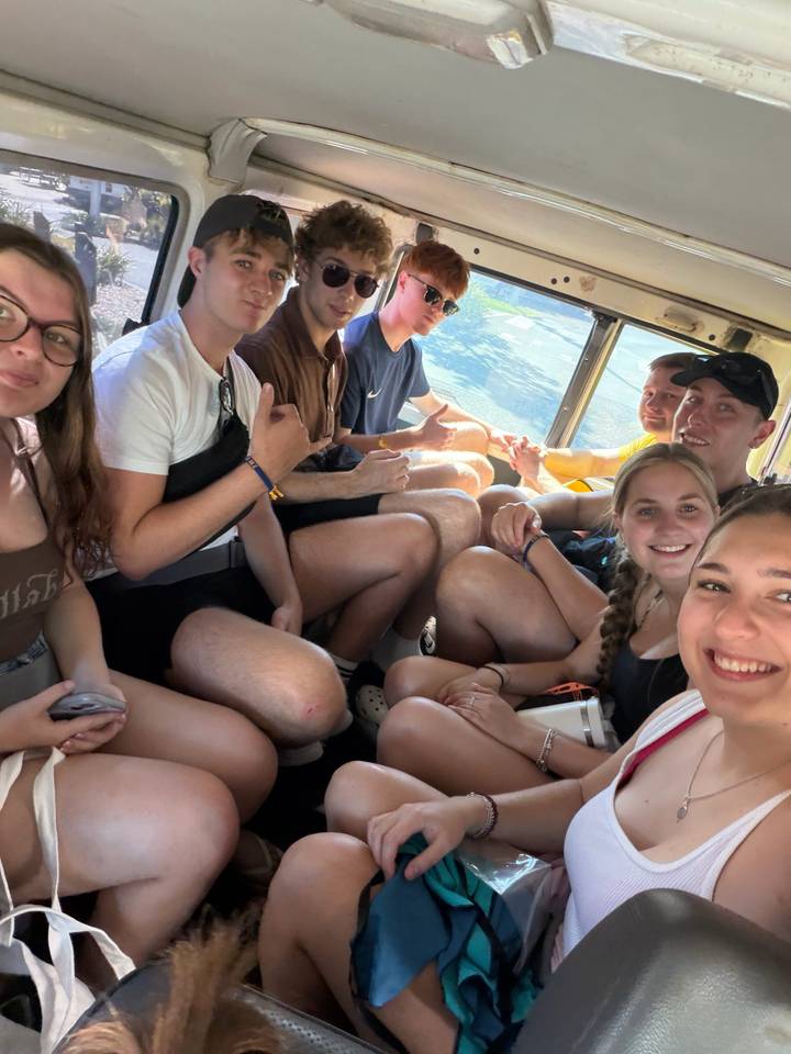 Travellers smile inside crowded open vehicle during tour transfer