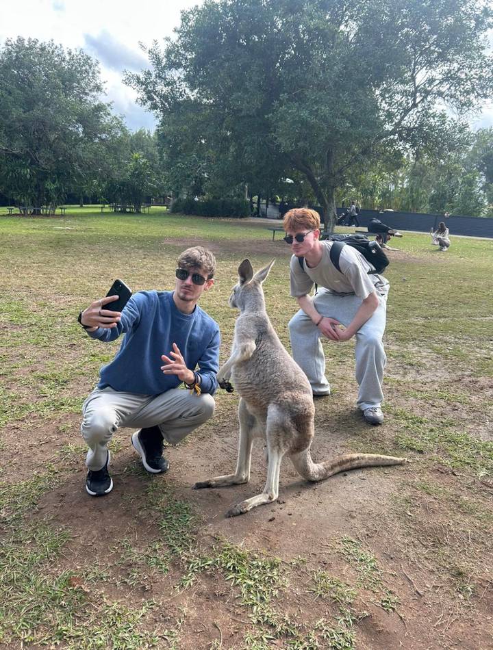 Travellers take selfie with curious kangaroo in grassy park