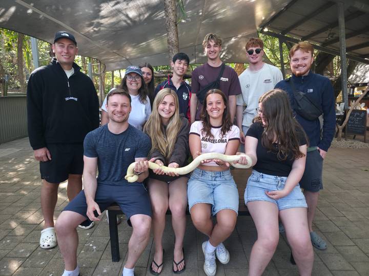 Tour group holds a long snake during wildlife demonstration