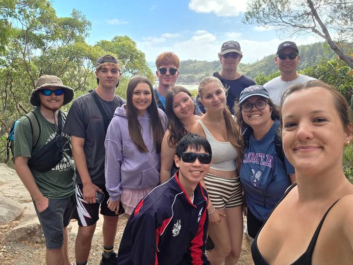 Hiking group poses on rocky viewpoint surrounded by lush tropical foliage