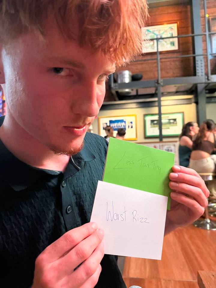 Man holds handwritten green note in casual bar setting