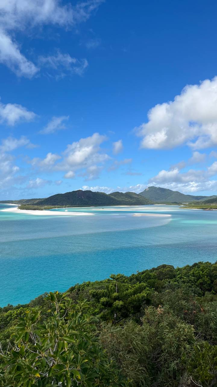 Turquoise channels and white sand flats bordered by green islands under a bright blue sky