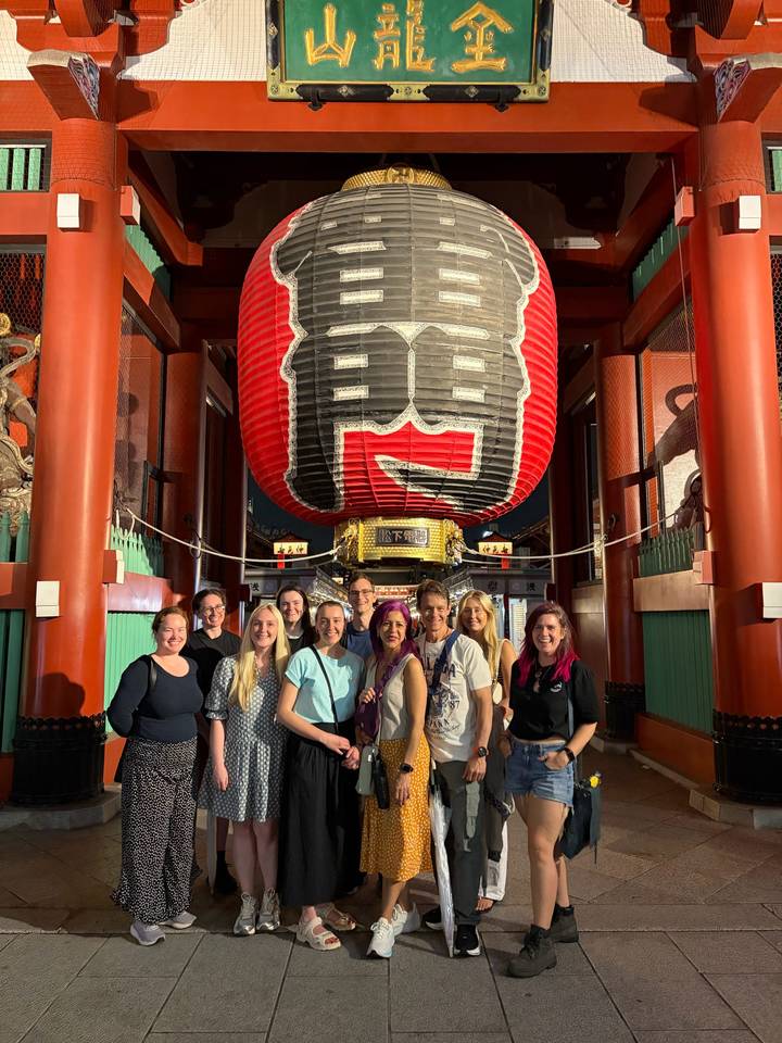 Tour group poses beneath the giant red lantern at the gate of Senso-ji Temple in Tokyo.