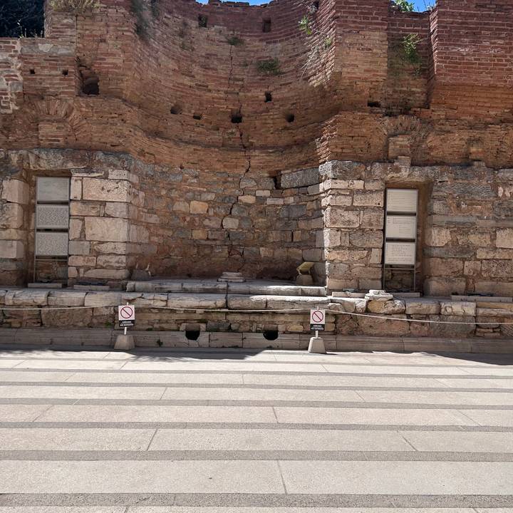 Section of an ancient stone wall and marble latrine with modern no-entry signs at Ephesus.
