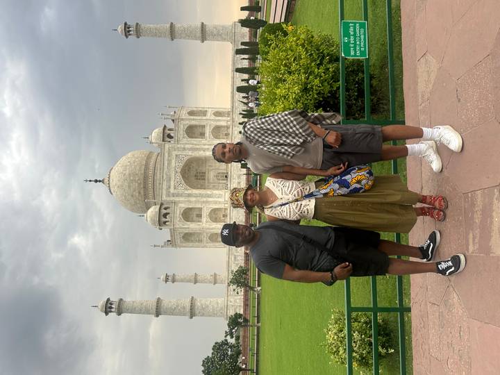 Friends pose for a snapshot with the Taj Mahal’s iconic dome and minarets rising behind them.