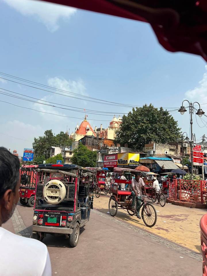Busy Indian street scene with colorful signboards, electric wires and distant temple spires.