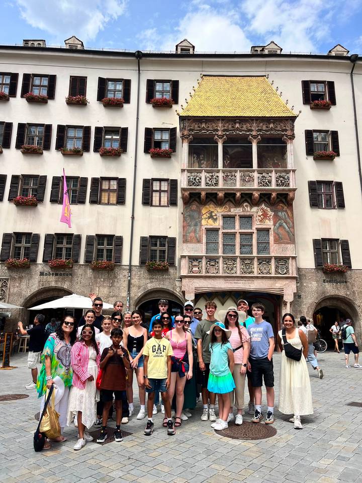 A large tour group poses in front of Innsbruck's ornate Golden Roof façade.