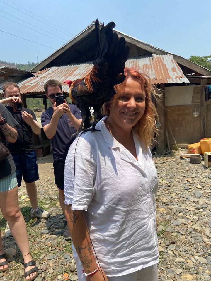 Woman with a bird on her shoulder, smiling.