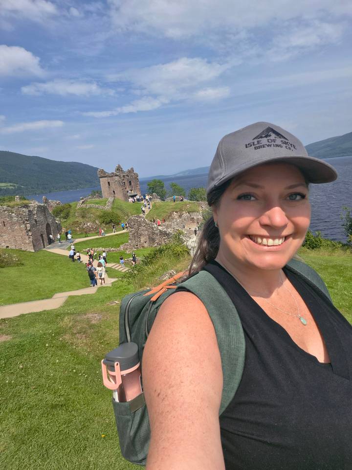 Selfie of traveler at Urquhart Castle ruins overlooking dark waters of Loch Ness.