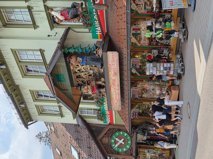 Tourists browse a whimsical shop fronted by oversized Black Forest–style figures and international flags.