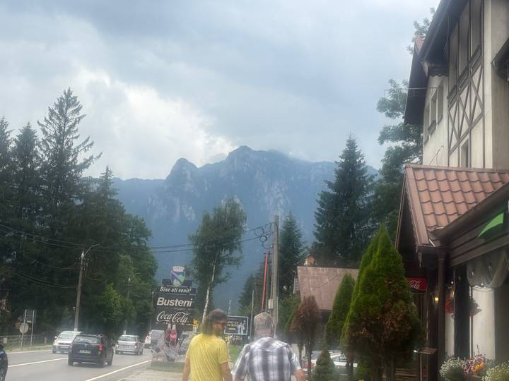 Hazy street scene in a mountain town with overcast sky and forested peaks in the background.