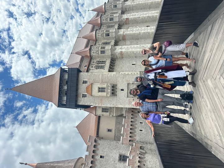 Tour group posing with a costumed knight on the wooden bridge of Corvin Castle.